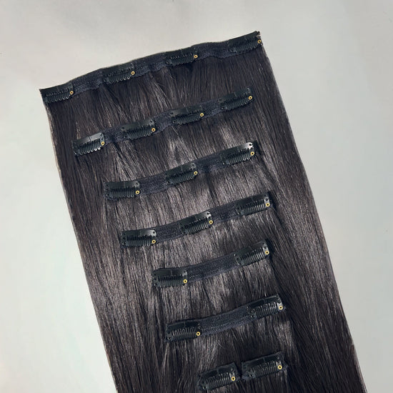 Set of black hair extensions on a gray background