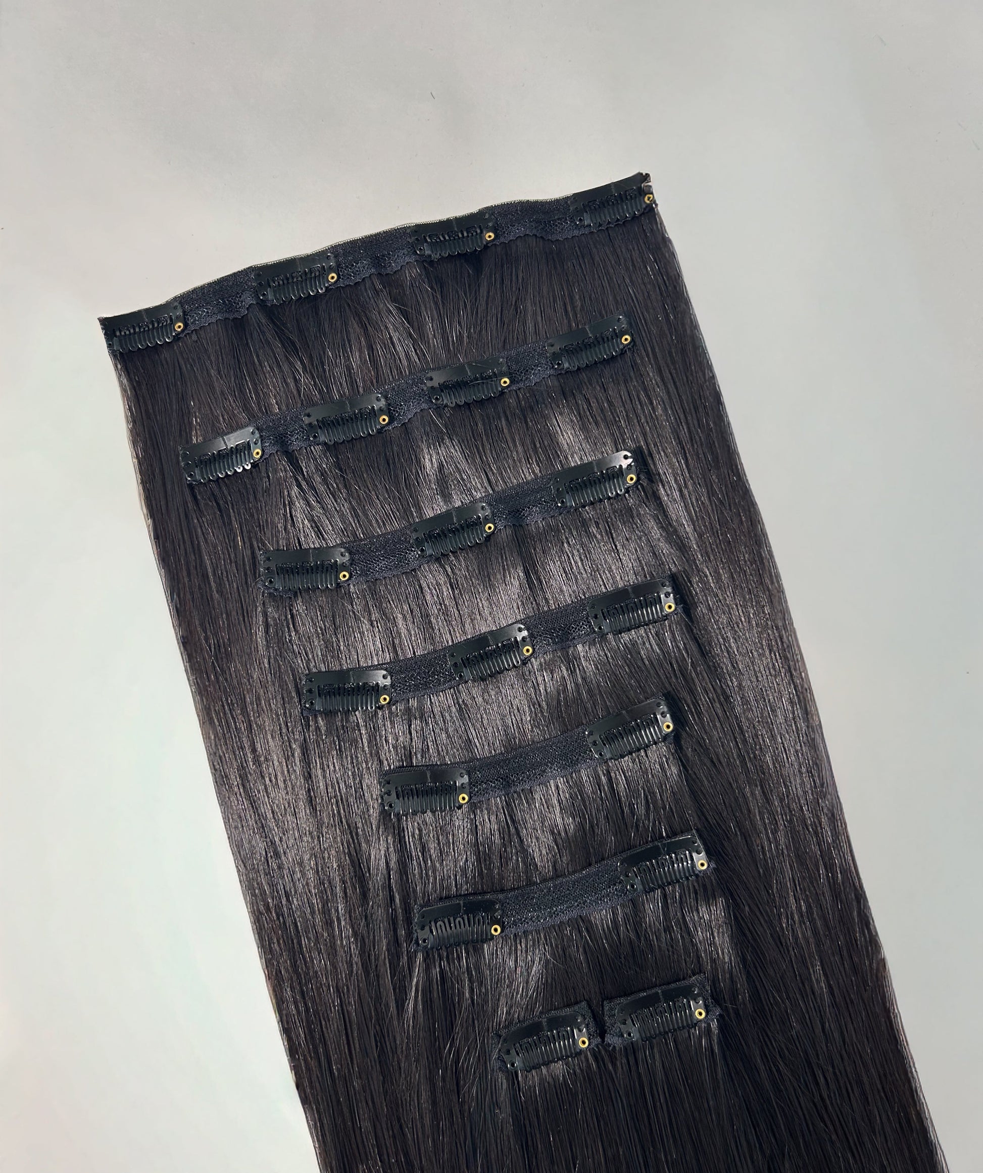 Set of black hair extensions on a gray background